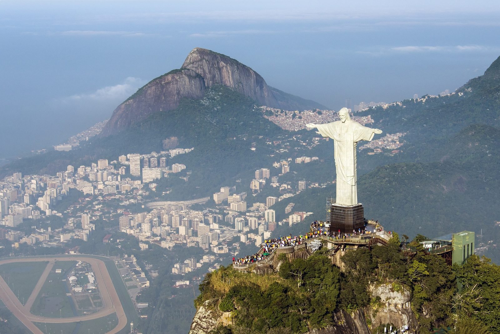 Vista aérea do Cristo Redentor no topo do Corcovado, com a cidade e as montanhas da zona sul do Rio ao fundo