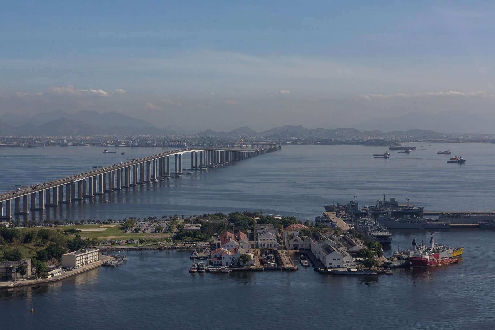 Vista aérea da Ponte Rio–Niterói atravessando a baía de Guanabara, com a Ilha de Mocanguê e navios em primeiro plano