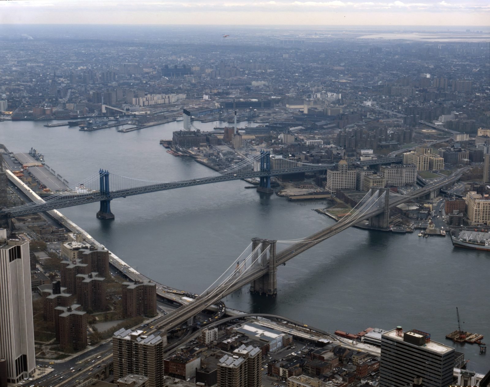 Vista aérea do East River com a Ponte do Brooklyn em diagonal no primeiro plano e a Ponte de Manhattan logo atrás